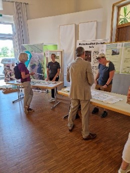 The actors are presenting and explaining their project content and their achievement  to other people during a trade fair.